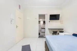 - une chambre blanche avec un lit et un bureau dans l'établissement Pousada Casa da Fernanda, Suíte Family, à Praia Grande