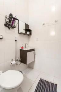 Baño blanco con aseo y lavamanos en Pousada Casa da Fernanda, Suíte Family, en Praia Grande
