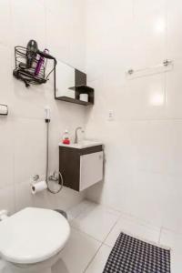 a white bathroom with a toilet and a sink at Pousada Casa da Fernanda, Suíte Family in Praia Grande