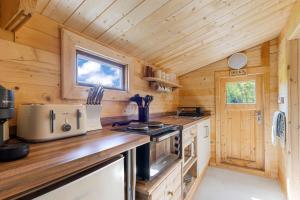 a kitchen in a tiny home with wooden walls at Choller Lake Lodges - Sunbeam Cabin With Private Hot Tub in Arundel