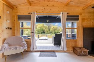 a room with a large window in a wooden house at Choller Lake Lodges - Sunbeam Cabin With Private Hot Tub in Arundel