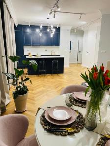 una sala de estar con una mesa con platos y flores en Warsaw Sadyba Premium Apartment by B2, en Varsovia