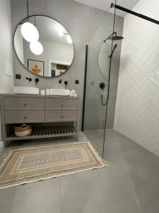 een badkamer met een douche, een wastafel en een spiegel bij Warsaw Sadyba Premium Apartment by B2 in Warschau