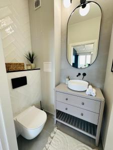 W łazience znajduje się umywalka, toaleta i lustro. w obiekcie Warsaw Sadyba Premium Apartment by B2 w Warszawie