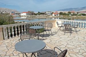 a patio with tables and chairs on a balcony at Lokunja Bed&Breakfast in Pag