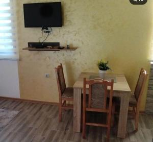 a dining room table with chairs and a television on the wall at Apartman NIKOLIJA 2 in Kaludjerske Bare