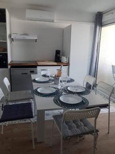 eine Küche mit einem Tisch mit Tellern und Stühlen in der Unterkunft Canet plage T2 + cabine clim et piscine in Canet-en-Roussillon