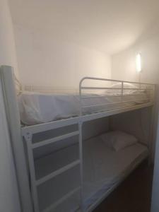 ein weißes Etagenbett mit weißer Bettwäsche und Kissen darauf in der Unterkunft Canet plage T2 + cabine clim et piscine in Canet-en-Roussillon