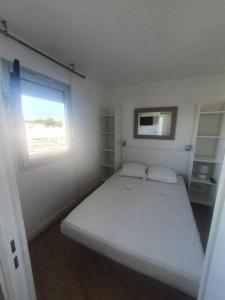 ein kleines Schlafzimmer mit einem weißen Bett und einem Fenster in der Unterkunft Canet plage T2 + cabine clim et piscine in Canet-en-Roussillon