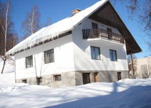 un bâtiment blanc avec un toit recouvert de neige dans l'établissement Ubytování v Jeseníkách - Bělá pod Pradědem, à Adolfovice