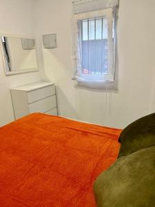 a bedroom with a bed with an orange blanket and a window at Casa Brisa del mar in Puerto de Sagunto