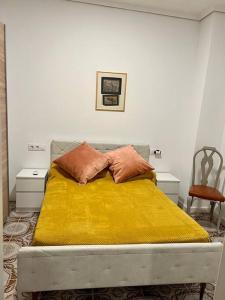 a bed with a yellow blanket and two pillows on it at Casa Brisa del mar in Puerto de Sagunto