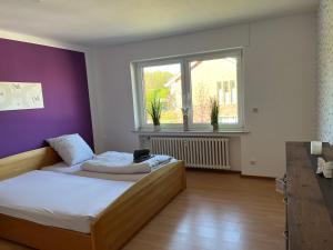 - une chambre avec un lit et un mur violet dans l'établissement Apartment Geronimo, à Werne