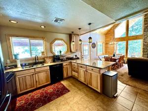 a large kitchen with wooden cabinets and a living room at Tranquil Cabin - Private Hot Tub And Fire Pit! in Duck Creek Village