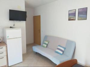 a living room with a blue couch and a flat screen tv at Studio apartmani Ante in Zaostrog