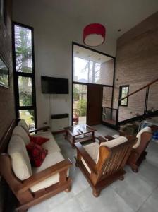 uma sala de estar com um sofá e cadeiras e uma televisão em Casa en Country “El Pinar” em Santa Fé