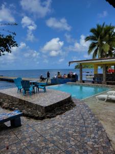 a swimming pool with a table and chairs next to the ocean at ScubaPortobelo in Portobelo