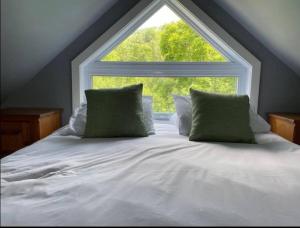 a bed with two pillows in front of a window at Tremblant Village Retreat!Steps to hill & trails in Mont-Tremblant