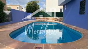 a swimming pool in front of a blue house at SA TORRETA 3 in Cala Blanca