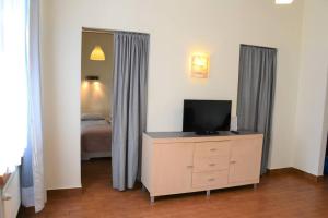 a bedroom with a bed and a dresser with a television at Kaletnicza Old Town Apartment in Gdańsk