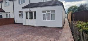 a white house with a door on a brick driveway at Self-contained guest suite in Eltham