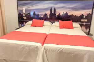 Cette chambre dispose de 2 lits avec des oreillers rouges et d'une fenêtre. dans l'établissement Hacienda Guadalquivir, à Cordoue