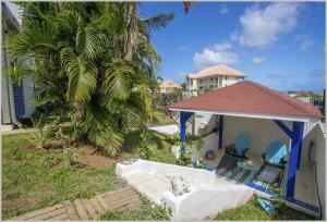 聖呂斯的住宿－Villa Mango 150 mètres plage à pied，一座带凉亭和两把椅子的房子,还有一棵棕榈树