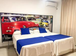 - une chambre avec un lit et une peinture de voitures dans l'établissement Hacienda Guadalquivir, à Cordoue