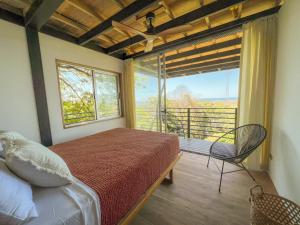 a bedroom with a bed and a large window at Ocean View Modern Jungle Vacation Home - Walking Distance to Playa Mal Pais in Mal País