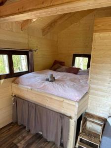 a bed in a log cabin with two windows at Treehouse Velké Losiny in Velké Losiny
