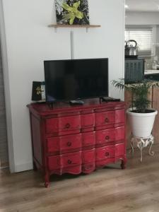 a red dresser with a flat screen tv on top at Gîte effet d’art in Saint-Privat