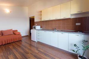 a kitchen with white cabinets and an orange couch at Apartments Alajbeg in Trogir