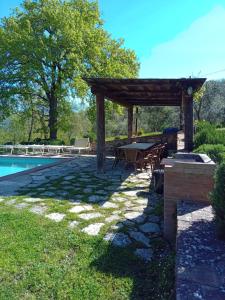 een pergola en een tafel naast een zwembad bij Podere Il Trebbio, porzione di villa in Gaiole in Chianti