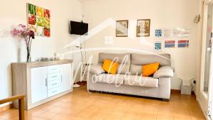 a living room with a gray couch and orange pillows at SA TORRETA 1 in Cala Blanca