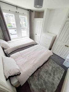 a small bedroom with two beds and a window at Stylish 2 Bedroom Maisonette in the heart of Gloucester Road in Bristol