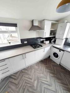 a kitchen with white cabinets and a stove top oven at Stylish 2 Bedroom Maisonette in the heart of Gloucester Road in Bristol