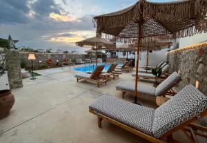 un patio avec des chaises et des parasols ainsi qu'une piscine dans l'établissement Koukounari Apartments, à Skala