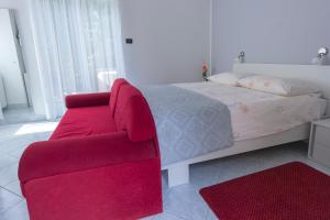 um quarto com uma cadeira vermelha e uma cama em Bed and Breakfast Rooms Sandalj em Mošćenička Draga