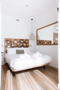 1 dormitorio con 1 cama blanca grande y espejo en Outsite Ibiza, en Es Canar
