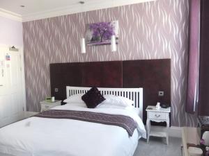 Un dormitorio con una cama grande y una pared morada y blanca en FourRooms - Couples Only en Blackpool