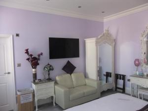 FourRooms - Couples Only في بلاكبول: غرفة معيشة فيها كرسي وتلفزيون على جدار