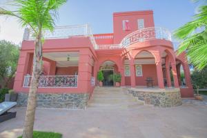 a pink house with a palm tree in front of it at Ferme Prestige in Moulay Yacoub