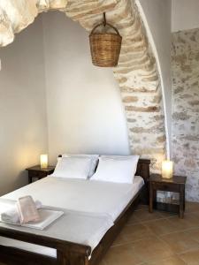 1 dormitorio con cama y pared de piedra en The Old barrel houses, en Citera