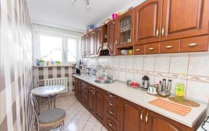 a kitchen with wooden cabinets and a sink and a table at Słoneczny Apartament in Szczecinek