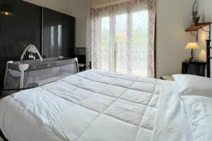 un grande letto bianco in una camera da letto con finestra di [Loano 2] parcheggio privato - wifi- giardino a Loano