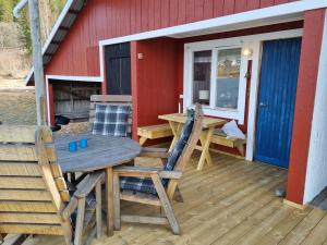 a wooden table and chairs on a deck with a red house at Boathouse in Mjällom