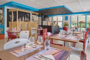 a restaurant with wooden tables and chairs with wine glasses at Kyriad Direct Le Havre Est - Gonfreville in Gonfreville-lʼOrcher