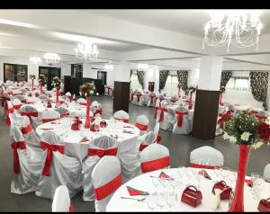 un gran salón de banquetes con mesas blancas y sillas blancas en ENIGMA BUCOVINEI, en Vicovu de Jos