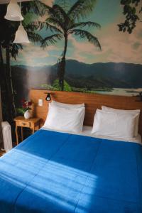 a bedroom with a blue bed with a painting at Villas da Bocaina in Bananal