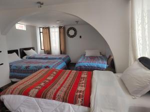库斯科Hostal Killaly Inn Cusco的带拱门的客房内的三张床